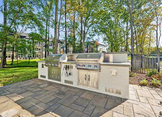 a barbecue grill in the middle of a patio with trees