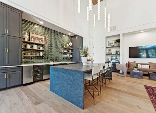 a kitchen with a blue island and a living room with a table and chairs