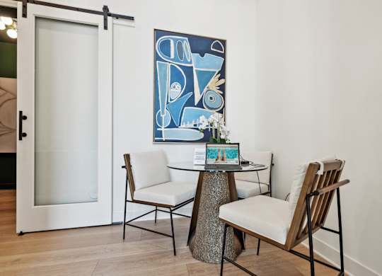 a dining room with a table and chairs and a painting on the wall