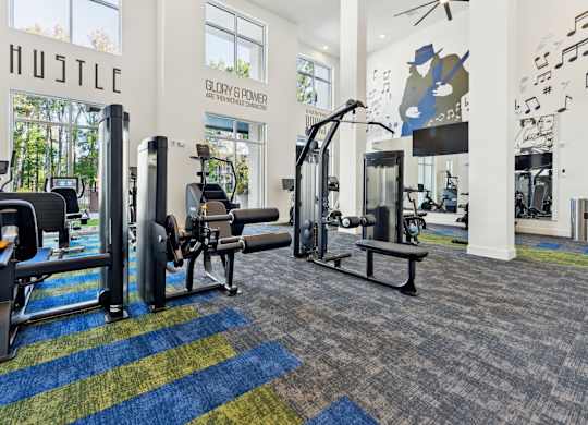 a gym with weights and cardio equipment in a building with large windows