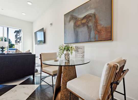 a dining room with a table and chairs and a painting on the wall