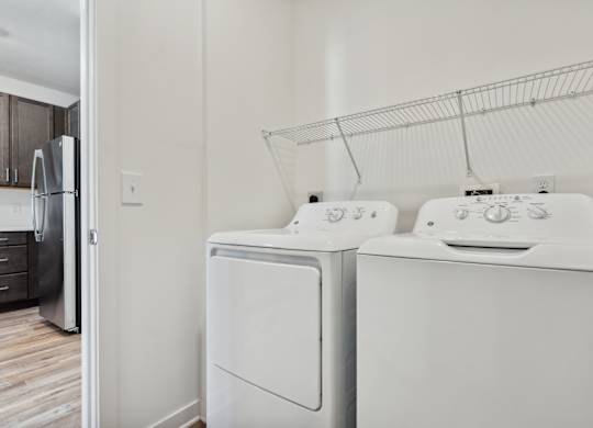 a white washer and dryer in a laundry room with a refrigerator