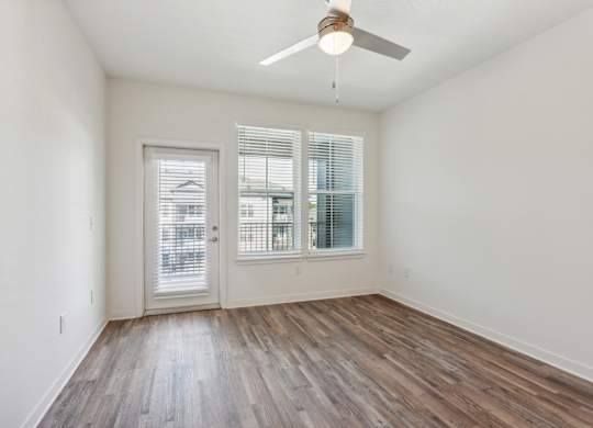 an empty living room with wood floors and a ceiling fan