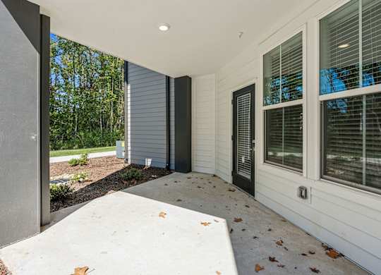the front porch of a house with a concrete walkway and a large window