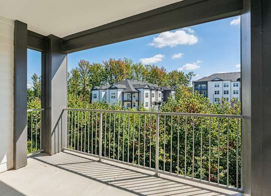 a balcony with a view of trees and houses in the distance