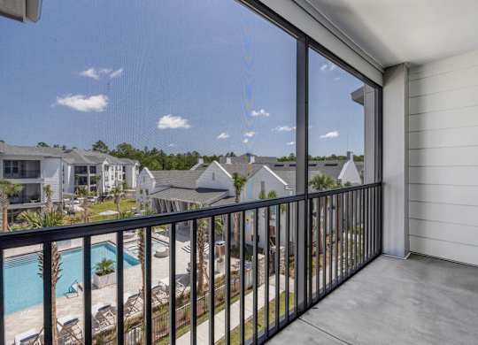A balcony with a view of a pool and houses.