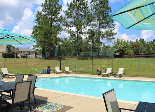 A pool surrounded by chairs and umbrellas at The Avery at Auburn in Auburn, AL
