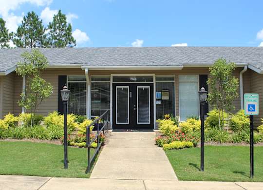 A building with a black door and a sign on the lawn.