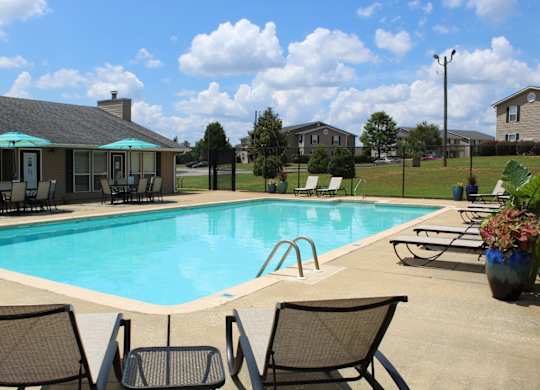 Pool with sundeck, tables, and chairs at The Avery at Auburn Apartments in Auburn, AL