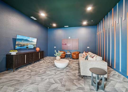 A modern living room with a grey carpet and a large painting on the wall.