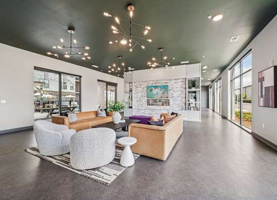 A spacious living room with a grey floor and a stone wall.