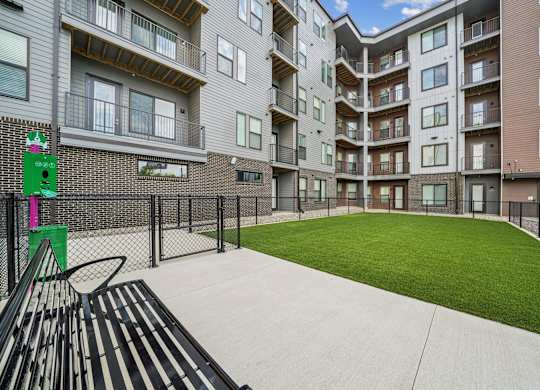 Apartment complex with a green lawn and a basketball hoop.