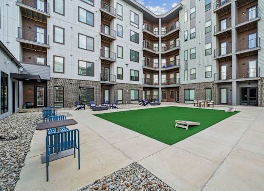 A courtyard with a green lawn and benches surrounded by apartment buildings.