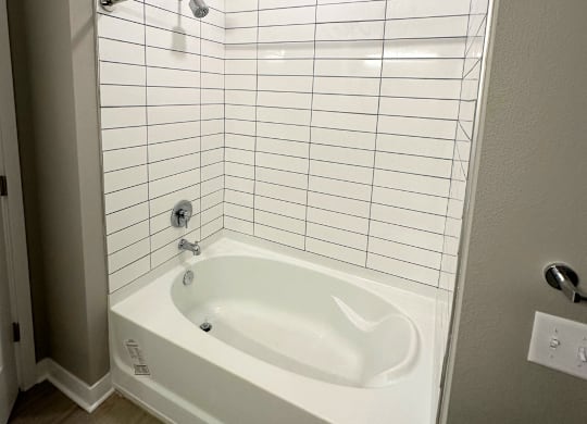 A white bathtub with a shower head and a shower curtain rod.