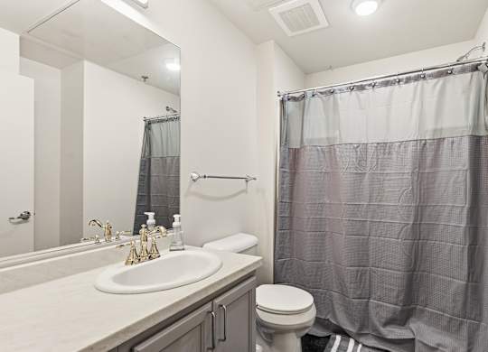 A bathroom with a sink, toilet, and shower curtain at The Tower Apartments, Alabama, 35401