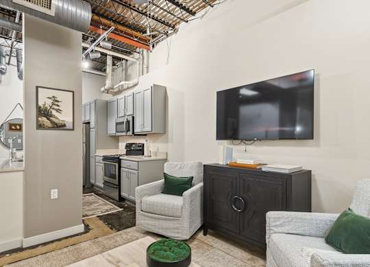 A living room with a television and a chair at The Tower Apartments, Alabama, 35401