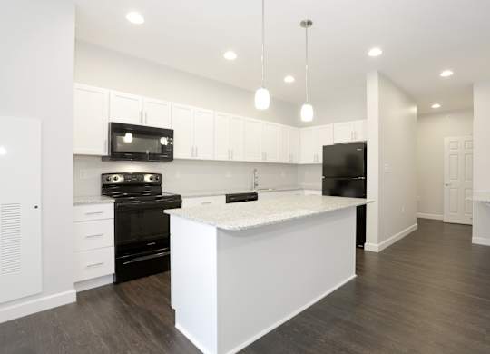 A modern kitchen with a white island and black appliances at Promenade at Founders Square Apartments in Indianapolis, IN