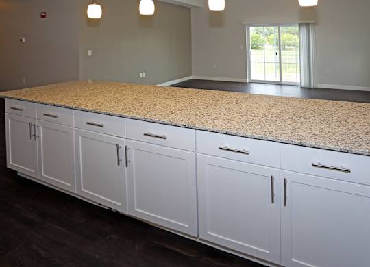 oversized breakfast bar with cabinets, pendant lighting, and granite countertop EV charging stations at Promenade at Founders Square Apartments in Indianapolis, IN