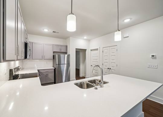 A modern kitchen with a white countertop and stainless steel appliances.