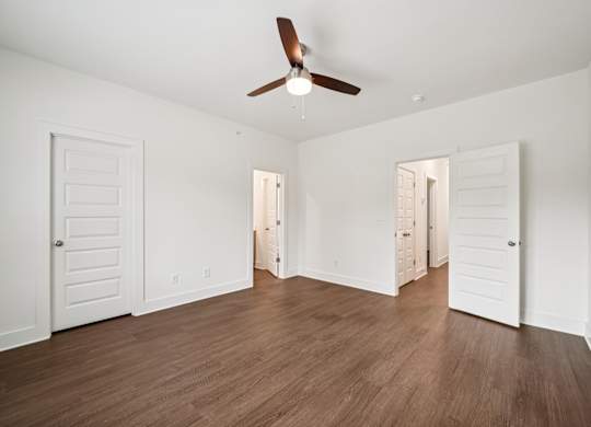 A room with a ceiling fan and wooden floors.