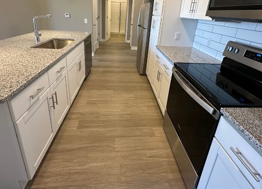 A kitchen with white cabinets and a black stove top oven at The Fitzroy Apartments in Birmingham, AL.