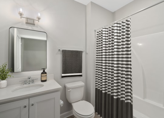 a bathroom with a shower and a toilet and a sink at The Cottages at Foley Farms apartments in Foley, AL