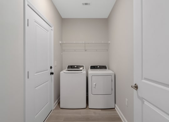 an empty laundry room with two washes and a dryer at The Cottages at Foley Farms apartments in Foley, AL