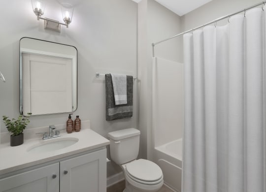 a bathroom with a shower and a sink and a toilet at The Cottages at Foley Farms apartments in Foley, AL