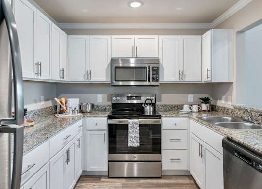 a kitchen with white cabinets and granite countertops