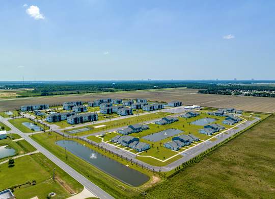 an aerial view of a housing complex in a grassy area next to a body of water