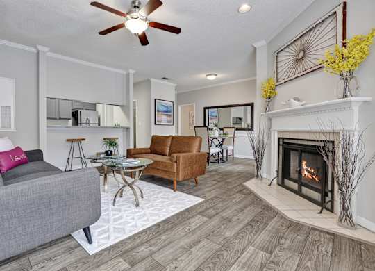 A living room with wood-style flooring, ceiling fan, and fireplace at Village at Caldwell Mill in Birmingham, AL