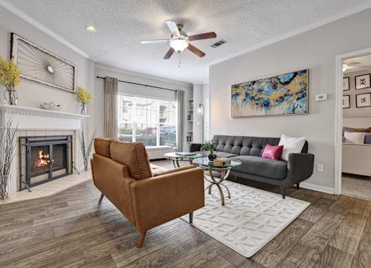 A living room with wood-style flooring, ceiling fan, and fireplace at Village at Caldwell Mill in Birmingham, AL