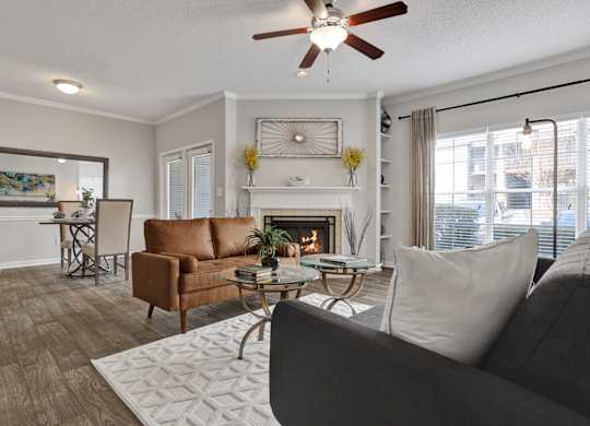 Living room and dining room with ceiling fan plank flooring and fireplace at Village at Caldwell Mill in Birmingham, AL