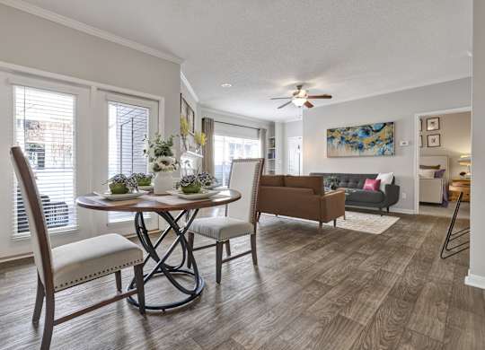 A dining room and living room with wood-plank flooring and ceiling fan at Village at Caldwell Mill Apartments in Birmingham, AL