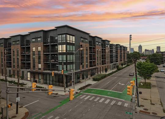 A street view of a city with apartment buildings, a crosswalk, and traffic lights.