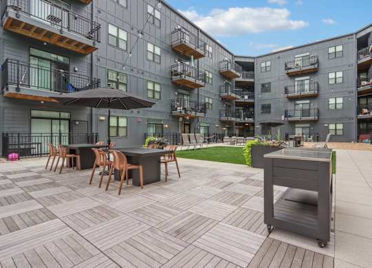 A patio with a table and chairs is surrounded by apartment buildings.