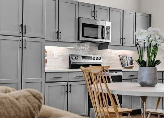 A modern kitchen with custom cabinets, tile backsplash, and stainless steel appliances at West Row Townhomes and at West Row Townhomes at West Row Lofts and Townhomes in Birmingham, AL