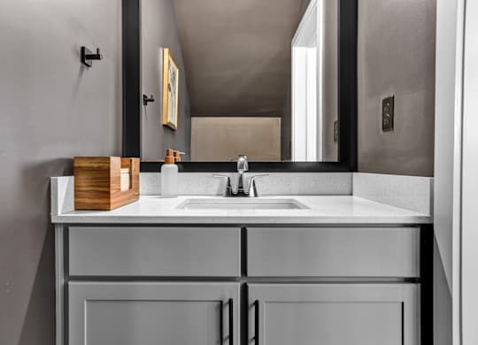 A modern bathroom with a undermount sink, framed mirror, and quartz countertops at West Row Lofts and Townhomes in Birmingham, AL.