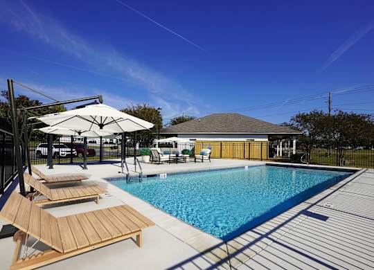 A pool with sun loungers and a white umbrella.