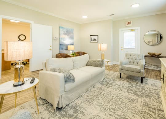 A living room with a white couch, a grey armchair, and a coffee table.