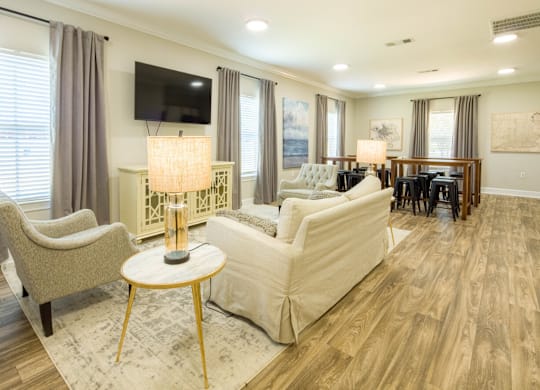 A living room with a white couch, a chair, a table, and a television.
