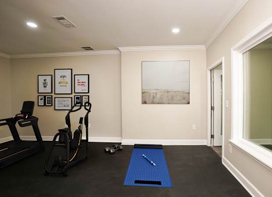 A room with a treadmill, exercise bike and a yoga mat.