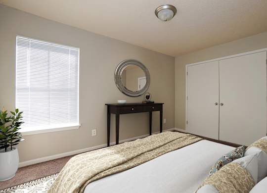 A bedroom with a bed, desk, and mirror.