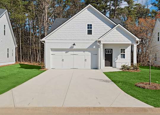 A white house with a grey roof and a garage door.