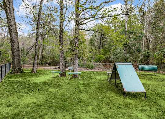 an interactive bark park with a picnic table and a bench in the woods
