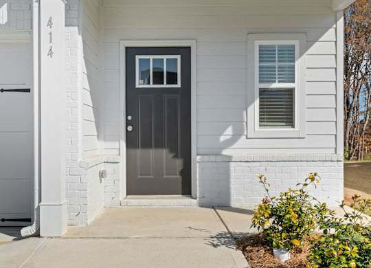 A white house with a black door and a window above the door.