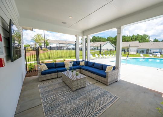 a covered patio with couches and a table next to a pool