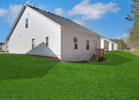 A white barn with a grey roof and a green lawn in front.