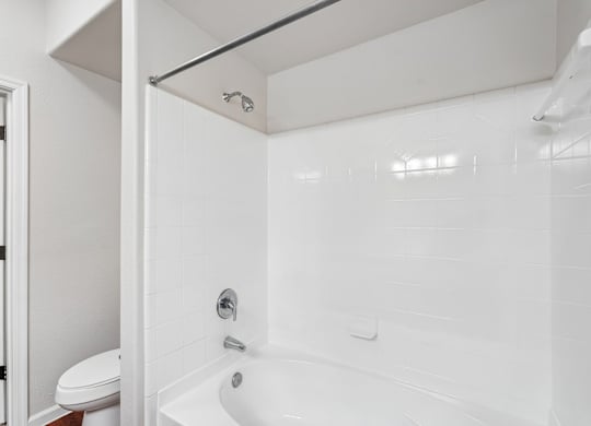 A white bathroom with a toilet and a bathtub.