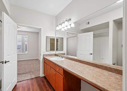 A bathroom with a sink, mirror, and wooden cabinets.